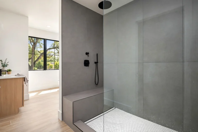 Bathroom design idea — modern walk-in shower with frameless glass panel, rainfall showerhead, built-in bench and large gray tiles